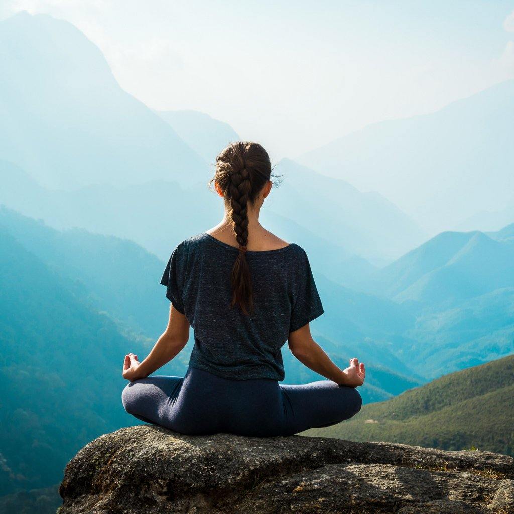 Girl mediating over mountains