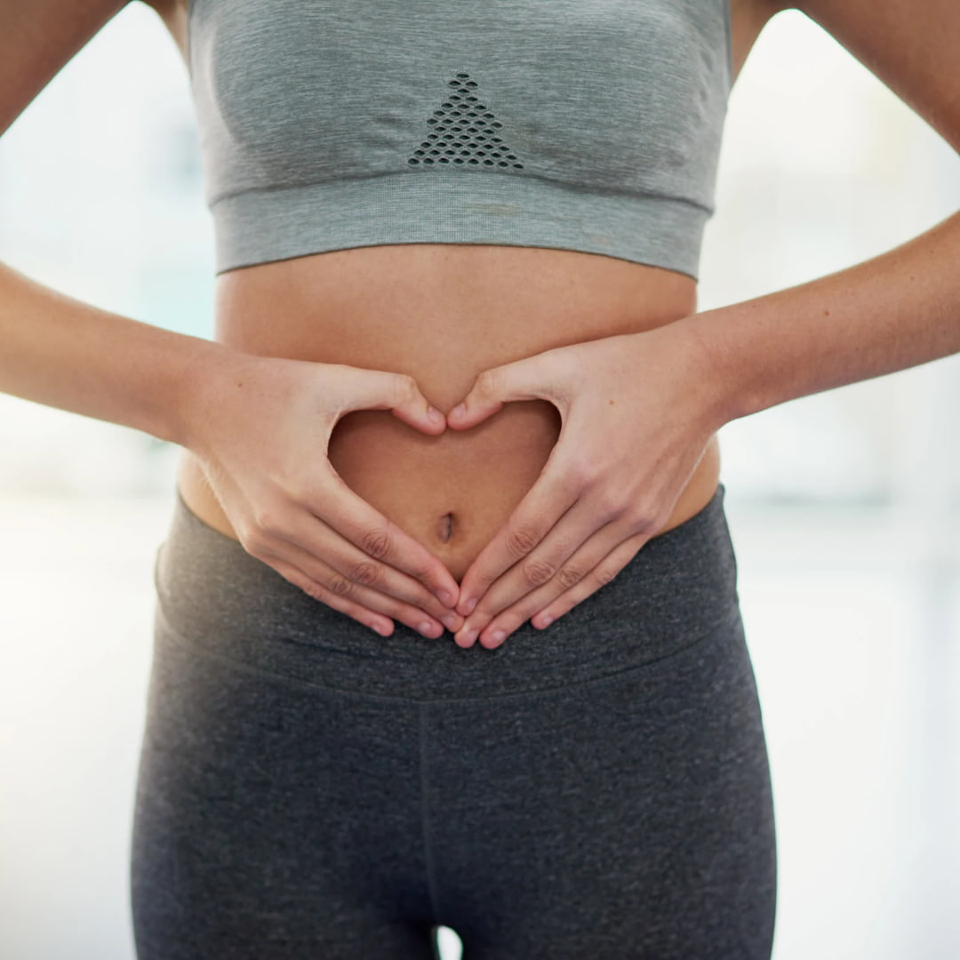 Women making a heart with her hands over a healthy gut